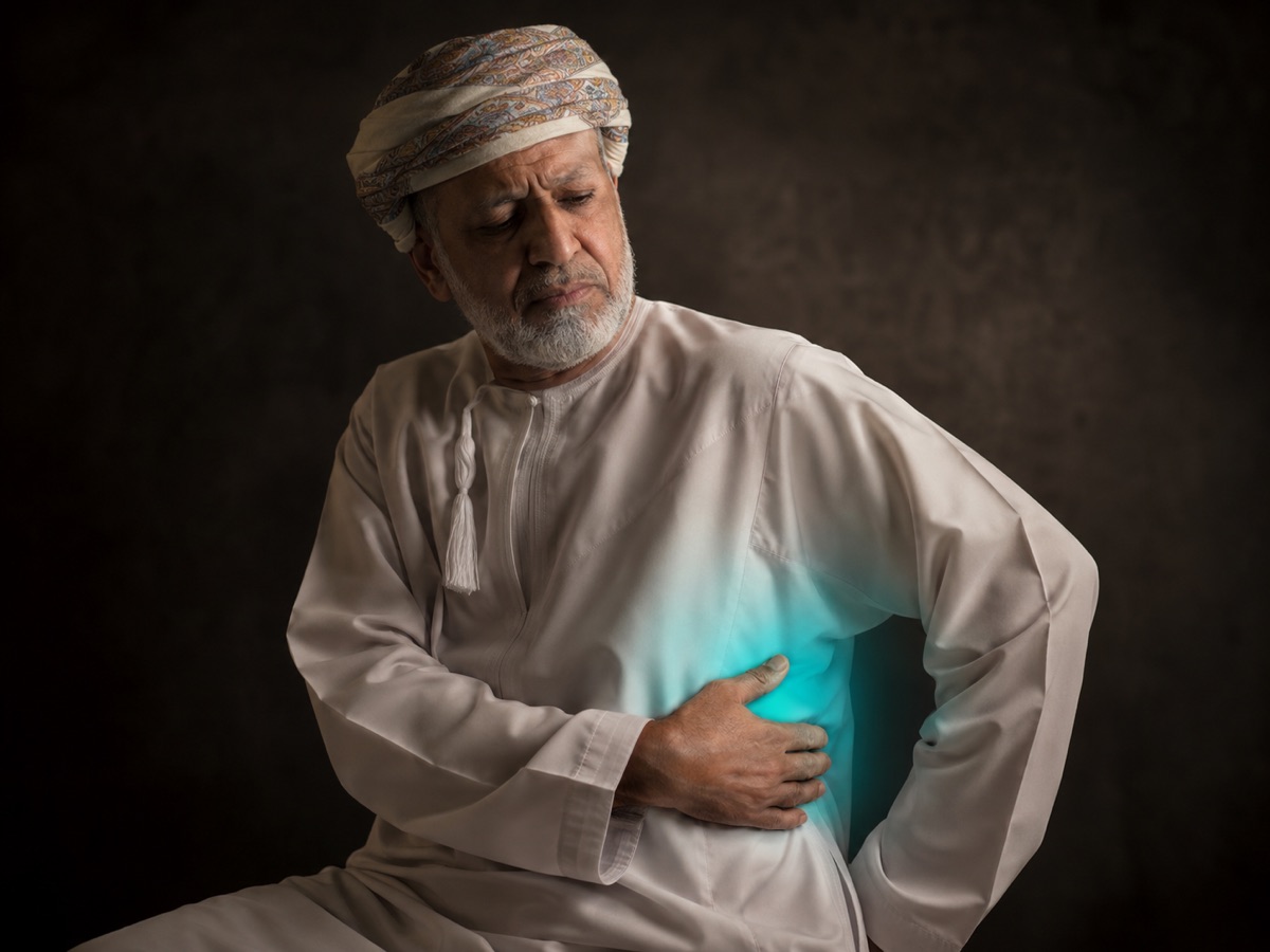 An older man pressing a hand to his side from the persistent burning pain of post-herpetic neuralgia.